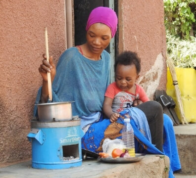Eine junge Mutter nutzt einen der effizienten Kochöfen von UpEnergy zum Kochen © UpEnergy